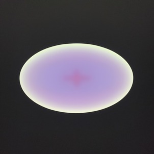 A glowing oval sculpture mounted on a wall. Its yellow at the edges and purple in the center.